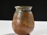 a brown vase sitting on a table with a black background