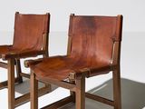 two brown leather chairs sitting next to each other on a white surface