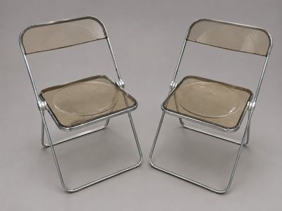une paire de chaises pliantes en chrome et en verre sur fond gris