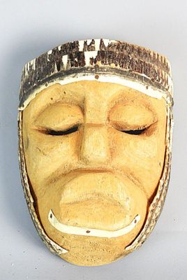 un masque en bois représentant un visage blanc sur un fond blanc