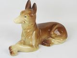une figurine représentant un chien couché sur une surface blanche