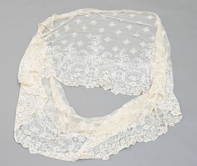 un gros plan d'un châle en dentelle blanche posé sur une surface grise