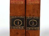 two old books sitting on top of each other on a white surface