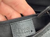 someone is holding a black purse with a leather label on it