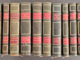 six vieux livres sont alignés sur une surface grise