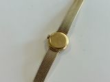 an image of a wrist watch with a gold dial on a white surface