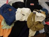 a pile of clothes that is sitting on a bed