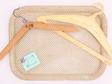 trois cintres en bois posés sur un sac beige