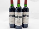 trois bouteilles de vin rouge posées sur une table blanche