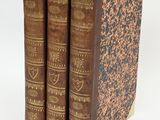 three old books sitting on top of each other on a white surface