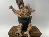 statue of a man sitting in a bucket with a turkey on top of it