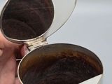 a person holding a silver cup with a mirror in it