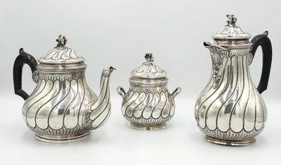 three pieces of silver tea and coffee set on a white surface