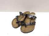 pair of black sandals with buckles on them on a white surface
