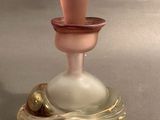 a small glass bottle with a pink top on a table