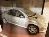 une voiture argentée avec un chien sur le siège conducteur, dans un garage