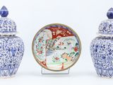 three blue and white vases and a plate on a stand