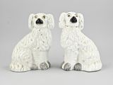 une paire de figurines de chiens en céramique blanche posées sur une surface grise