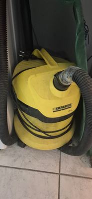 a yellow vacuum sitting on the floor next to a green hose