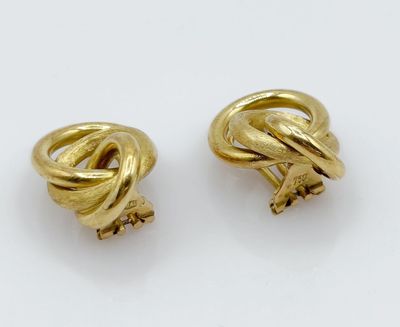 a pair of gold tone earrings with a knot design