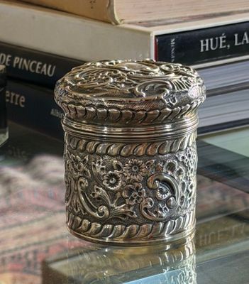 a silver box sitting on a glass table next to a pile of books