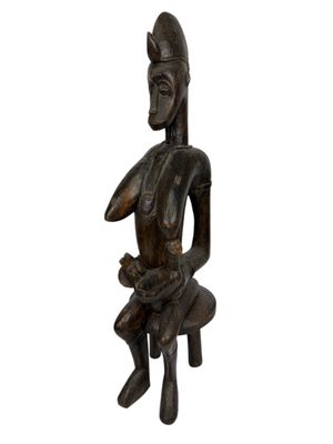 une image représentant une statue en bois d'une femme assise sur une chaise