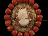 an image of a red and gold broochle with a woman ' s profile