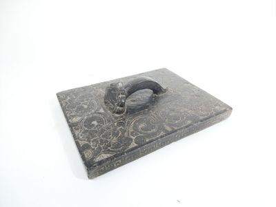 a black box with a ring on it on a white surface