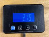 a digital clock on a wooden table with a charger