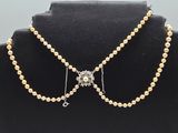 a necklace with pearls and a cross on a mannequin