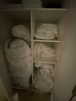 a closet full of white towels and blankets in it