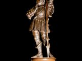 bronze statue of a man in armor holding a staff