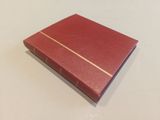 a red book sitting on top of a table next to a white table