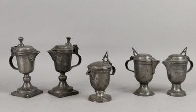 quatre tasses en argent sont alignées les unes à côté des autres sur une surface blanche