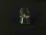a clear ring with a gold band sitting on top of a black surface