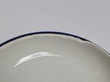 a white plate with a blue rim on a white table