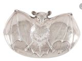 une assiette en argent sur laquelle est représentée une chauve-souris sur fond blanc