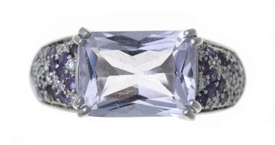 un gros plan d'une bague ornée d'une pierre violette entourée de diamants violets et blancs