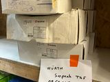 une pile de cartons posée sur une étagère, sur laquelle est accrochée une pancarte