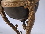 a gold and black vase on a stand on a white background