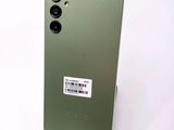 a close up of the back of a green phone with a sticker on it