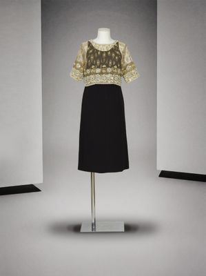 une robe noire et dorée posée sur un mannequin devant un mur blanc