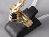 yellow gold ring with a blue sapphire and diamonds on top of a black piece of leather