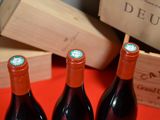 three bottles of red wine sitting on a table next to a wooden box
