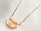 a close up of a gold necklace on a white surface