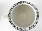 a white cup with a black and green design on it
