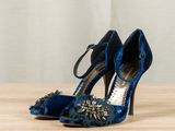 blue high heeled shoes on a wooden table with a white curtain in the background