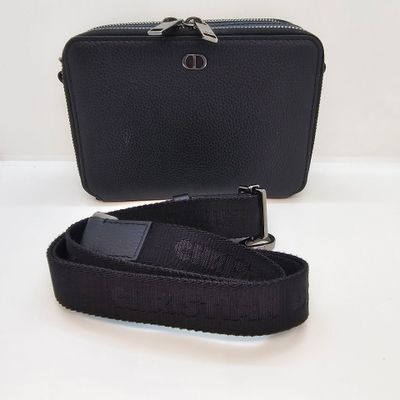 un sac à main noir muni d'une bandoulière et sur lequel est posé un téléphone portable