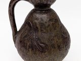 un vase marron avec une anse noire sur un fond blanc