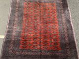 a red and black rug sitting on top of a cement floor
